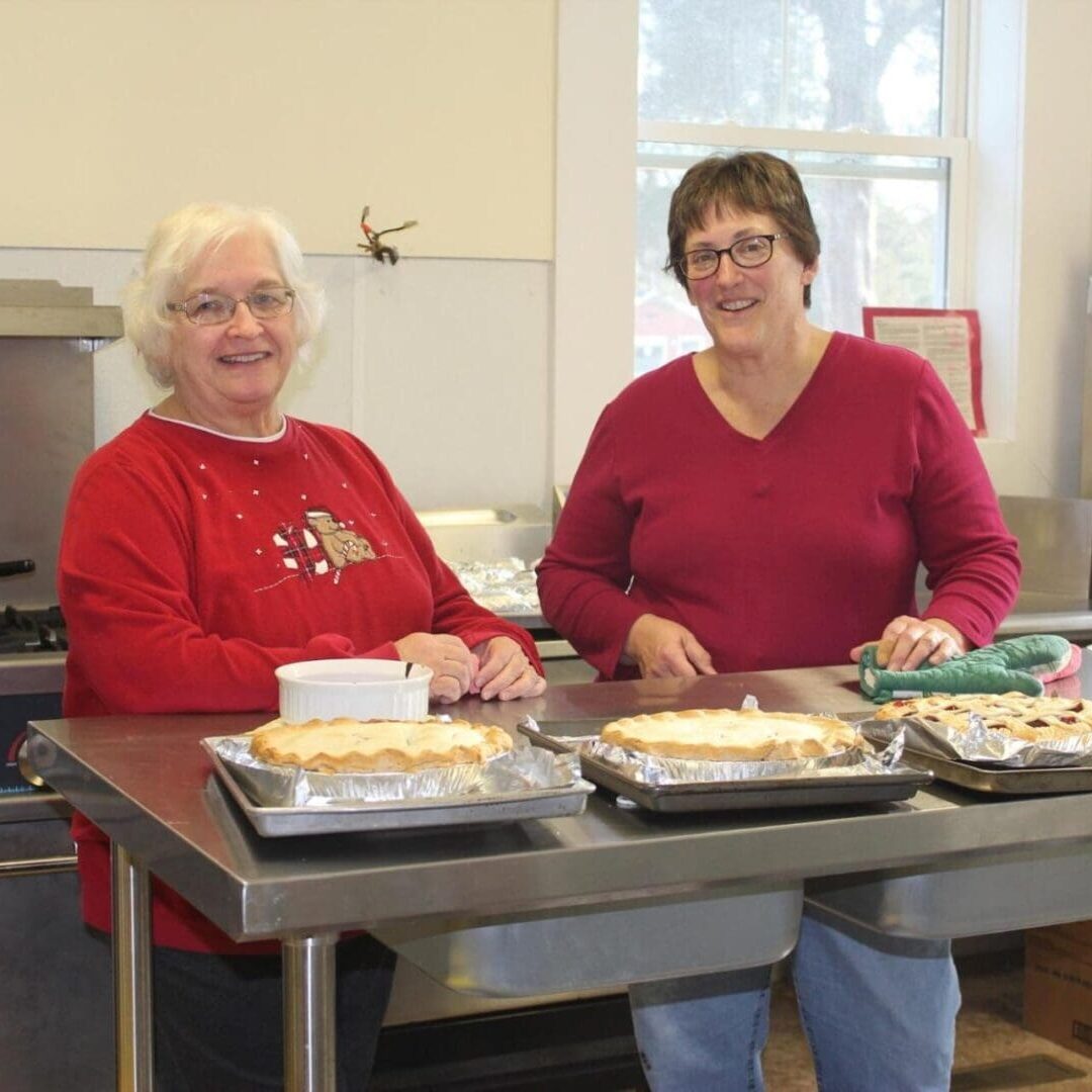 Two women sitting at a table with trays of food.